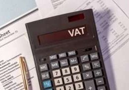 VAT word on display of calculator on papers documents and golden pen
